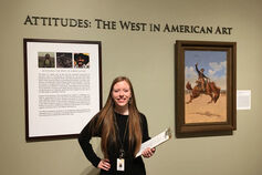 Female intern stands in front of American Art display.